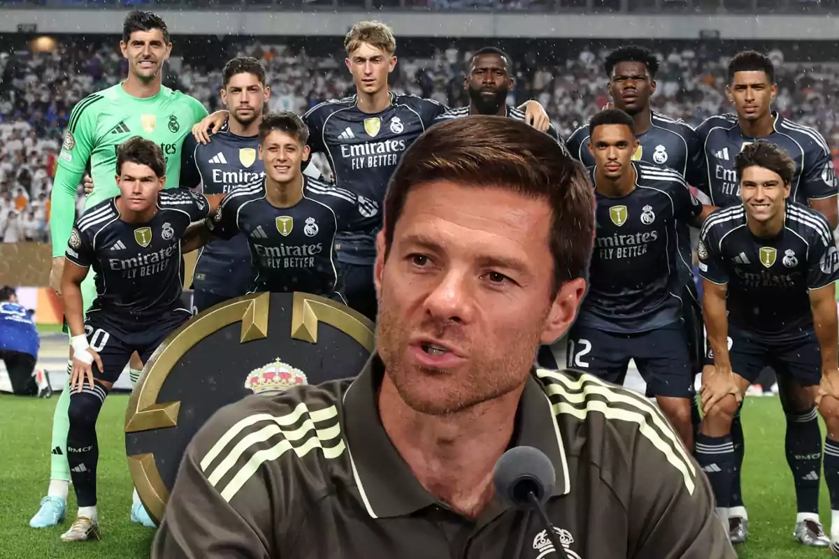 Un entrenador de fútbol aparece en primer plano mientras al fondo se ve a un equipo de jugadores del Real Madrid posando en el campo antes de un partido