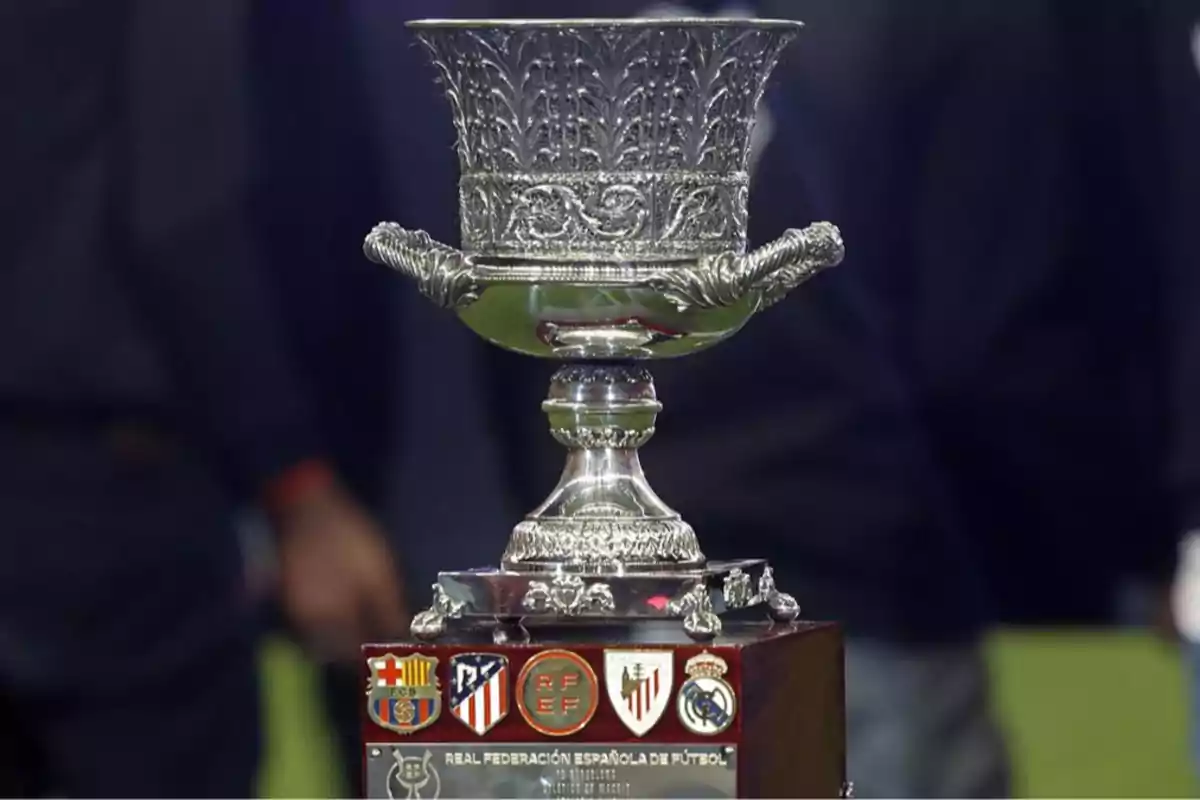 Trofeo plateado de la Supercopa de España de fútbol sobre una base con escudos de equipos Trofeo plateado de la Supercopa de España de fútbol sobre una base con escudos de equipos