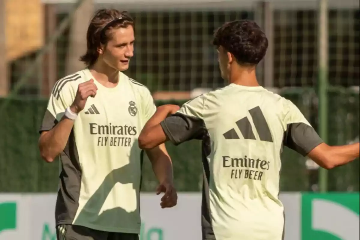 Dos futbolistas con uniforme de entrenamiento del Real Madrid conversan en el campo de entrenamiento Dos futbolistas con uniforme de entrenamiento del Real Madrid conversan en el campo de entrenamiento