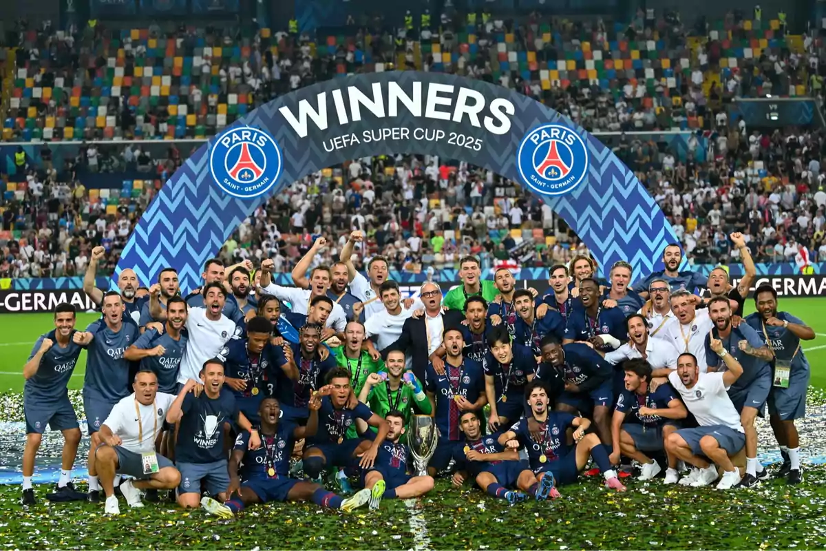 Jugadores y cuerpo técnico del Paris Saint-Germain celebran juntos en el campo tras ganar la Supercopa de la UEFA 2025 frente a un arco decorativo y con confeti en el suelo Jugadores y cuerpo técnico del Paris Saint-Germain celebran juntos en el campo tras ganar la Supercopa de la UEFA 2025 frente a un arco decorativo y con confeti en el suelo