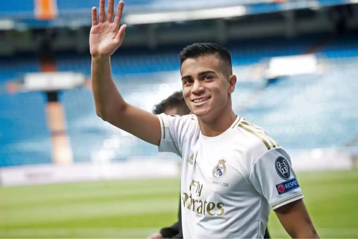 Jugador de fútbol con uniforme del Real Madrid saludando y sonriendo en un estadio