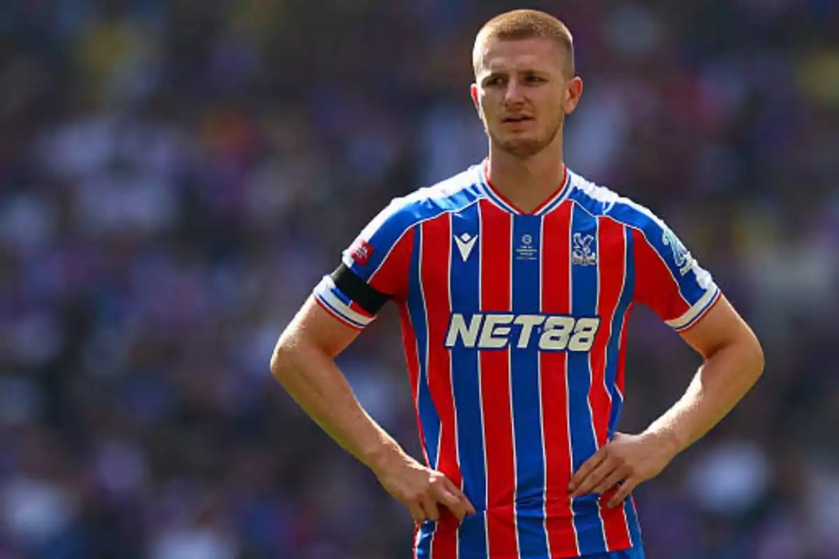 Soccer player wearing Crystal Palace’s red and blue striped uniform on the field during a match Soccer player wearing Crystal Palace’s red and blue striped uniform on the field during a match