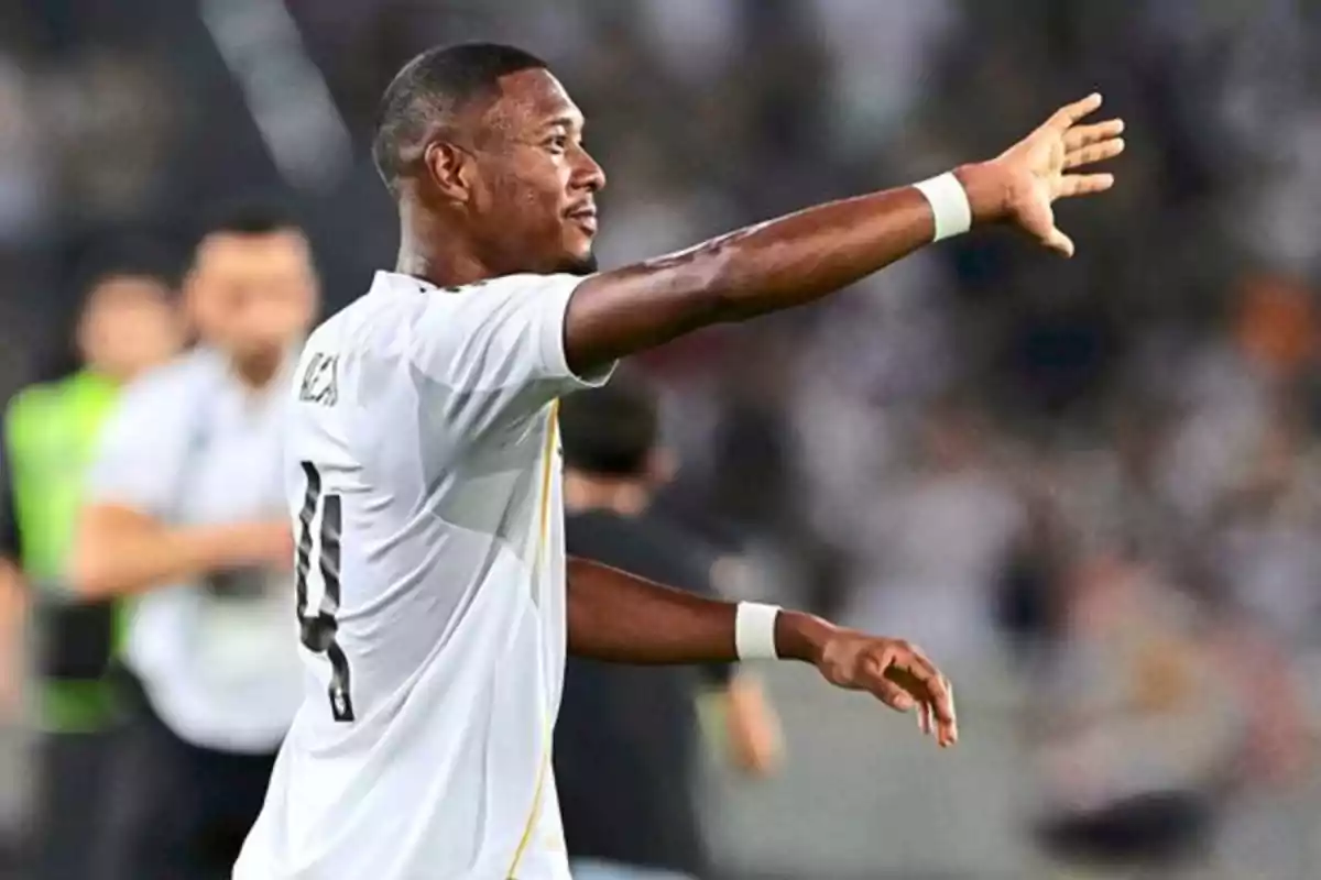 Soccer player in a white uniform celebrating on the field with an outstretched arm and a blurred background of people Soccer player in a white uniform celebrating on the field with an outstretched arm and a blurred background of people
