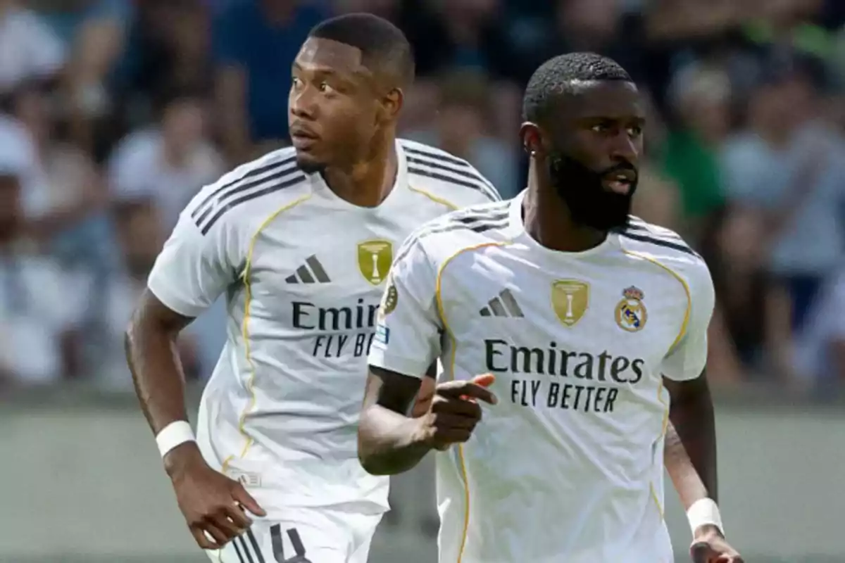 Two Real Madrid players run on the field during a match, both wearing the team’s white uniform with gold details.