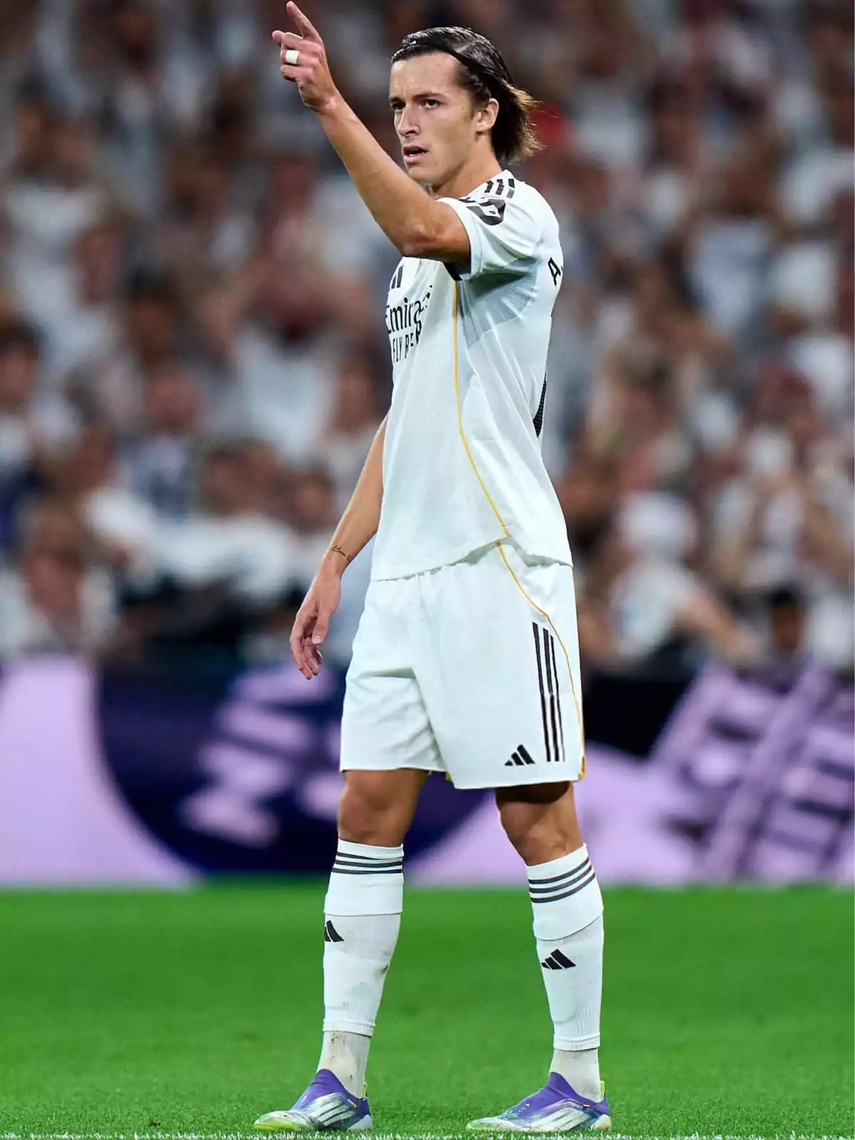 Soccer player in a white uniform pointing with his right arm during a match in a stadium full of spectators Soccer player in a white uniform pointing with his right arm during a match in a stadium full of spectators