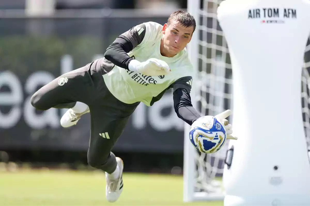 Soccer goalkeeper making a save during a training session with gloves and ball in hand in front of a goal and a training mannequin Soccer goalkeeper making a save during a training session with gloves and ball in hand in front of a goal and a training mannequin