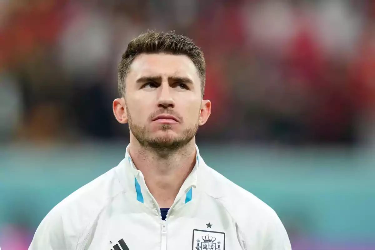 Soccer player wearing a white Spain national team jacket looking up in a stadium