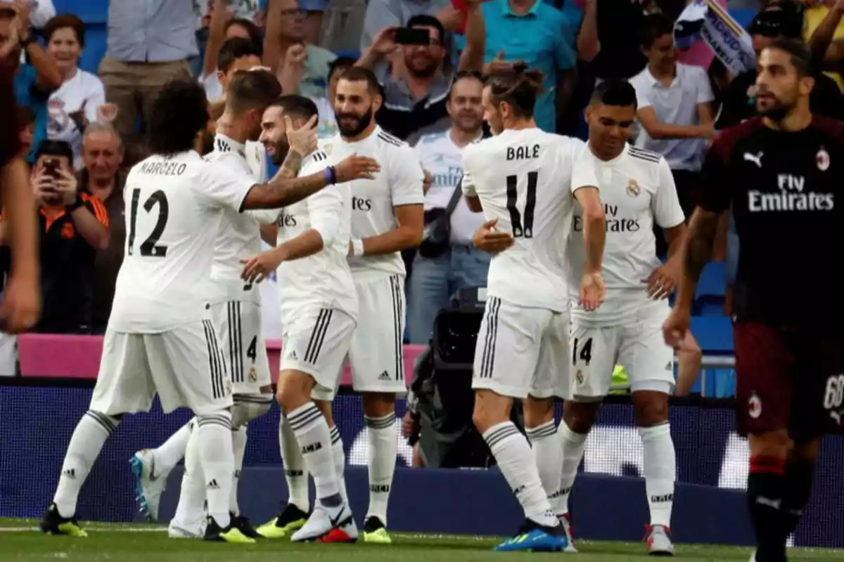 Real Madrid players celebrate a goal in a soccer match while the fans applaud in the stands. Real Madrid players celebrate a goal in a soccer match while the fans applaud in the stands.