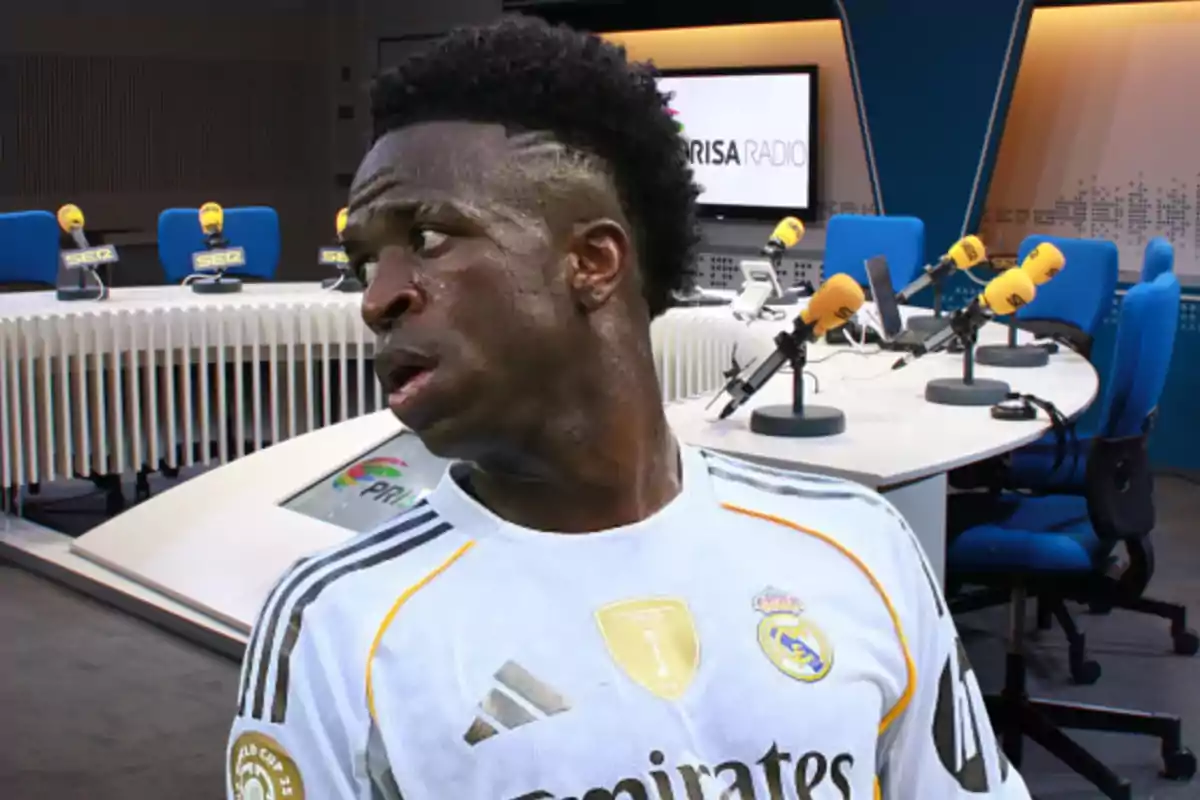A player wearing a white Real Madrid jersey appears in the foreground in front of a radio studio with yellow microphones and blue chairs.