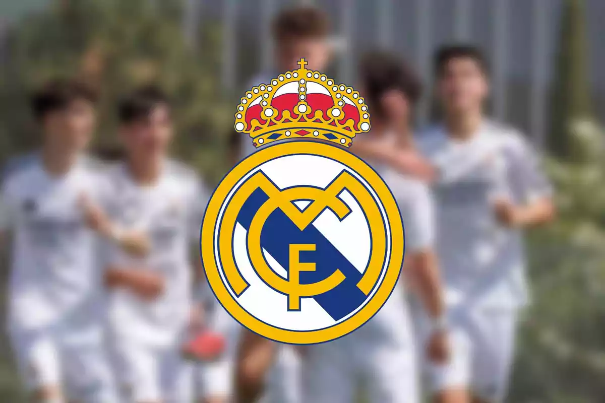 Jugadores de fútbol con uniforme blanco desenfocados y el escudo del Real Madrid en el centro enfocado