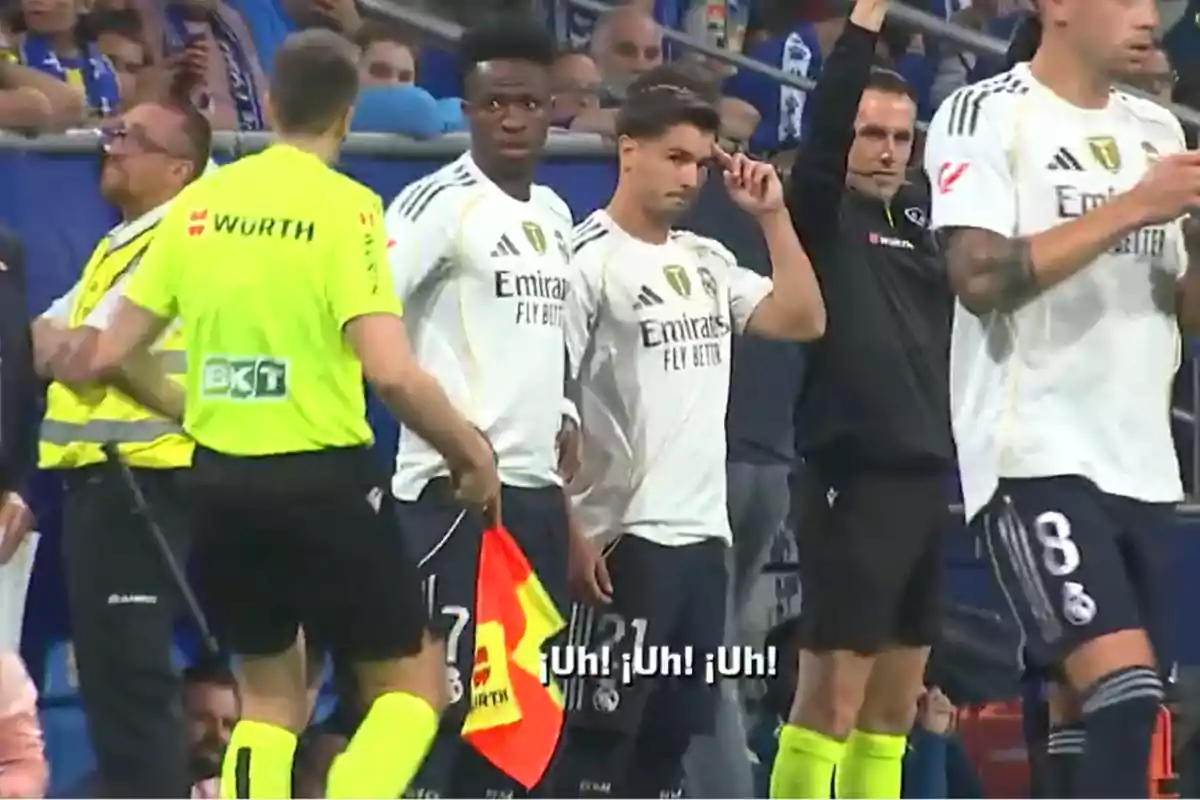 Real Madrid players on the sideline ready to enter the field alongside an assistant referee and security staff, with a crowd in the background and subtitles saying Uh Uh Uh