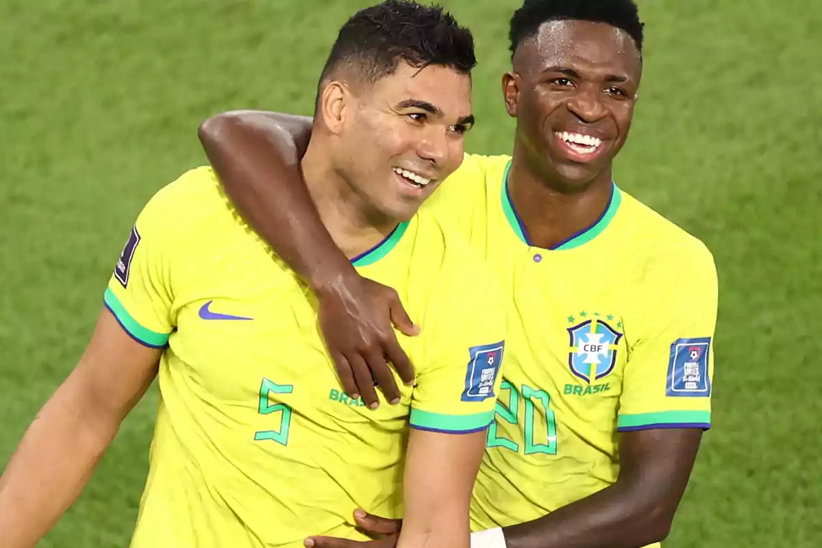 Two players from the Brazil national team smile and hug each other as they celebrate on the field.