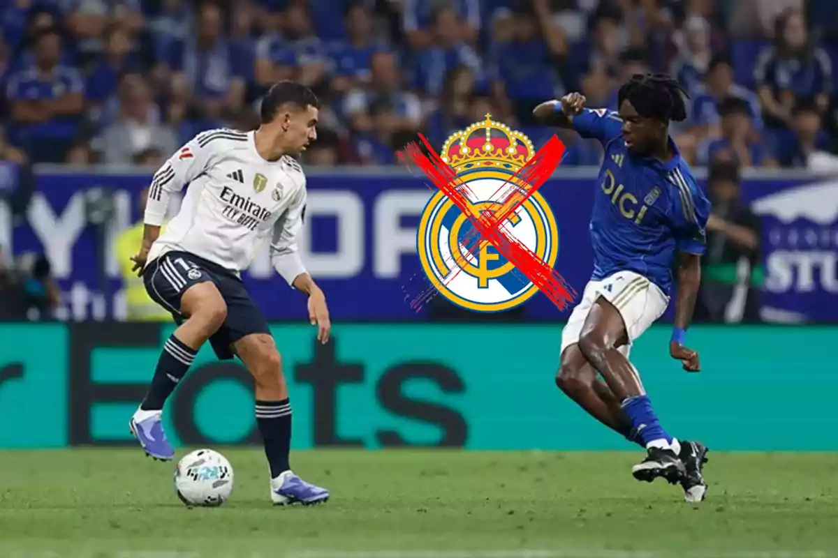 Dos futbolistas disputan el balón en un partido mientras el escudo del Real Madrid aparece en el centro con una gran equis roja encima