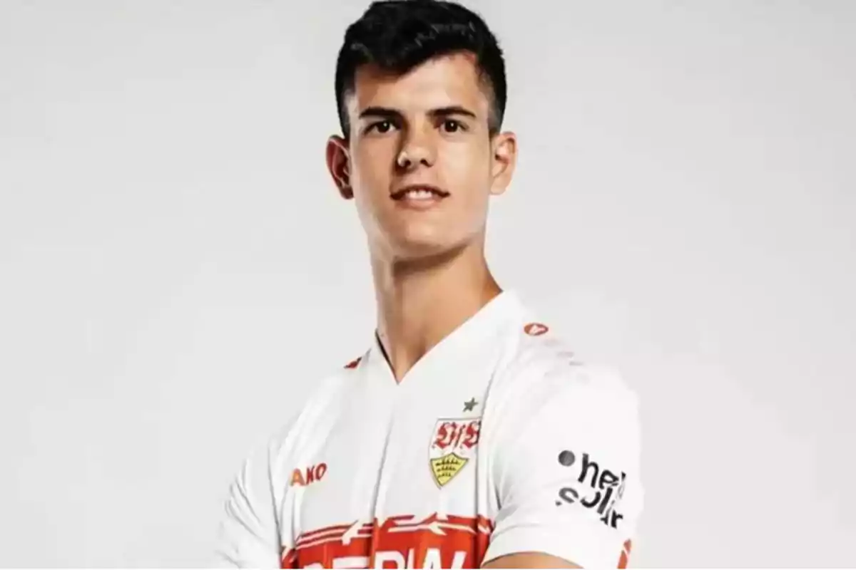Young man wearing a white soccer team jersey posing in front of a light background Young man wearing a white soccer team jersey posing in front of a light background