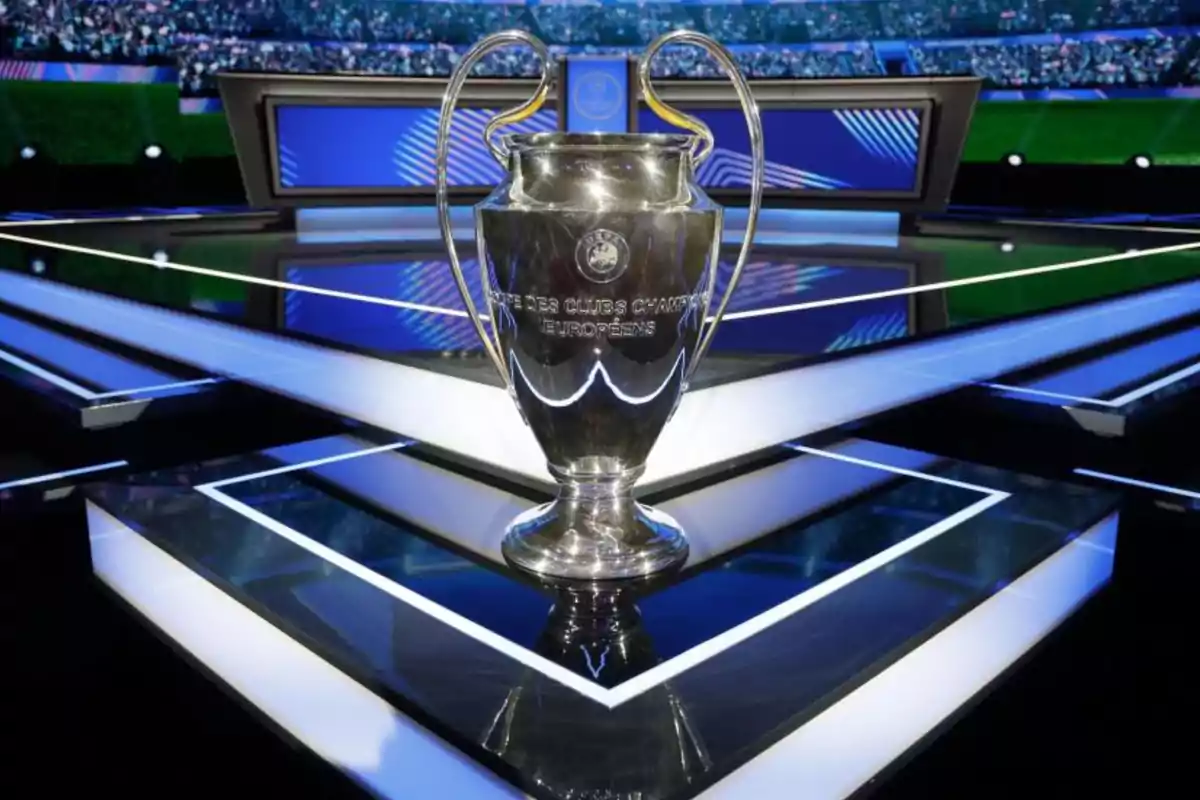 Champions League trophy on a lit platform in a stadium full of spectators