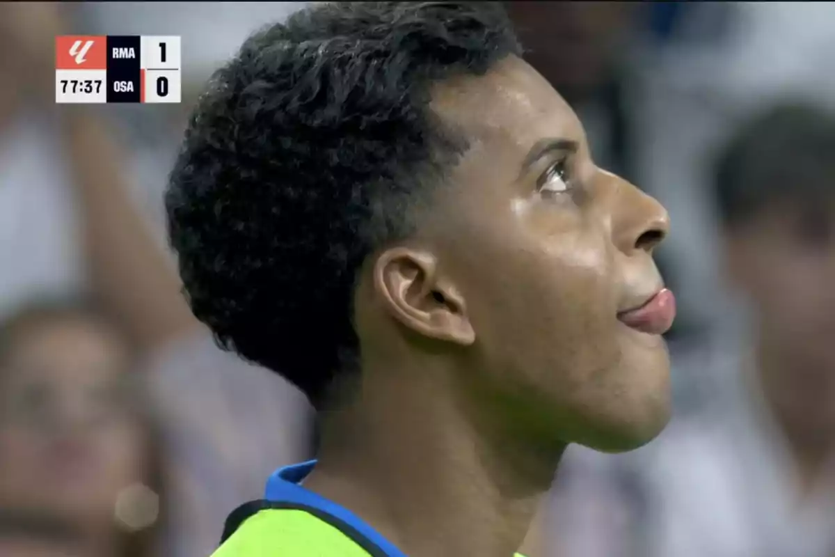 Soccer player looking up with his tongue out during a match, scoreboard in the corner shows Real Madrid leading 1-0 against Osasuna in the 77th minute and 37 seconds. Soccer player looking up with his tongue out during a match, scoreboard in the corner shows Real Madrid leading 1-0 against Osasuna in the 77th minute and 37 seconds.