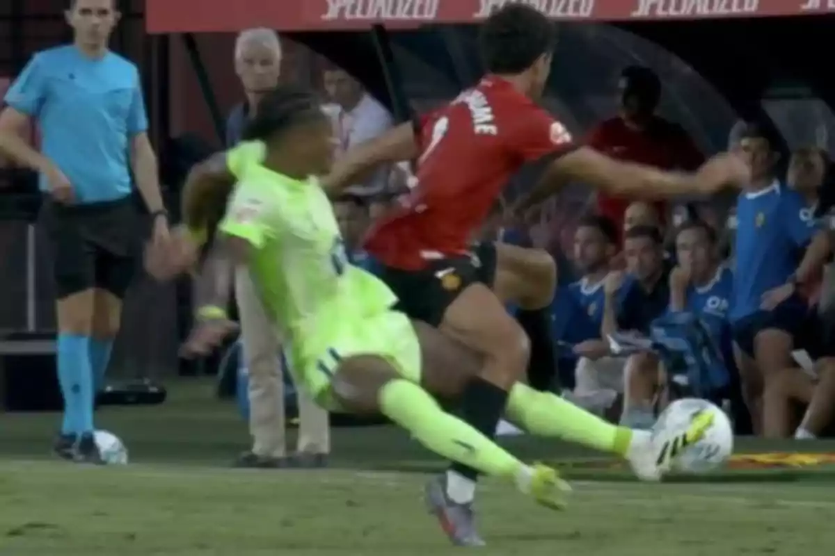 Two players fight for the ball in an intense play while a referee and several players watch from the background. Two players fight for the ball in an intense play while a referee and several players watch from the background.