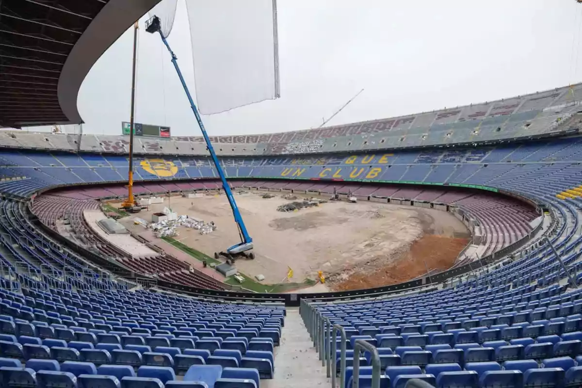 Soccer stadium undergoing renovation with cranes and machinery on the field and empty stands Soccer stadium undergoing renovation with cranes and machinery on the field and empty stands
