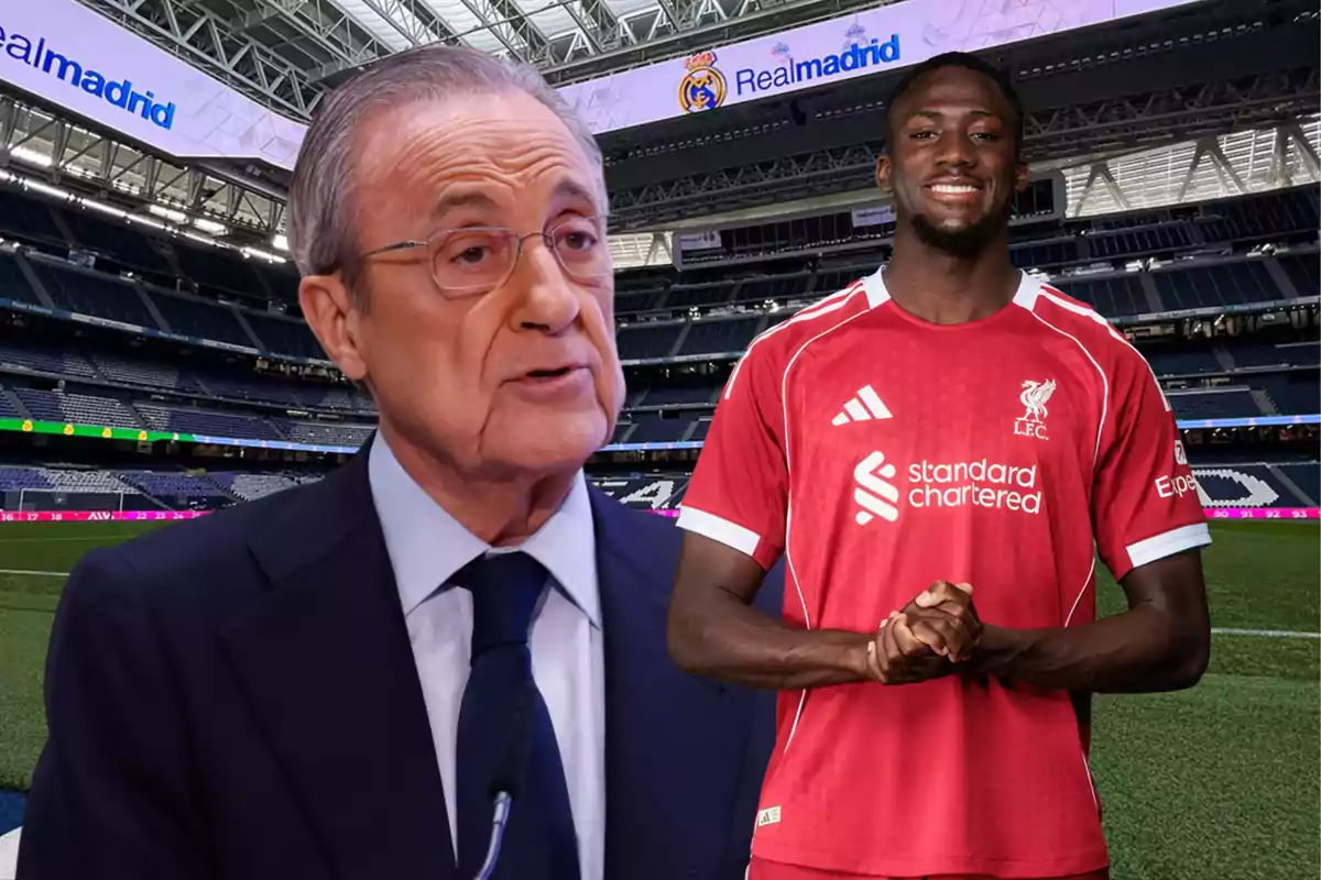 Un hombre de traje y un futbolista con uniforme rojo posan en un estadio con el logo de Real Madrid en el fondo