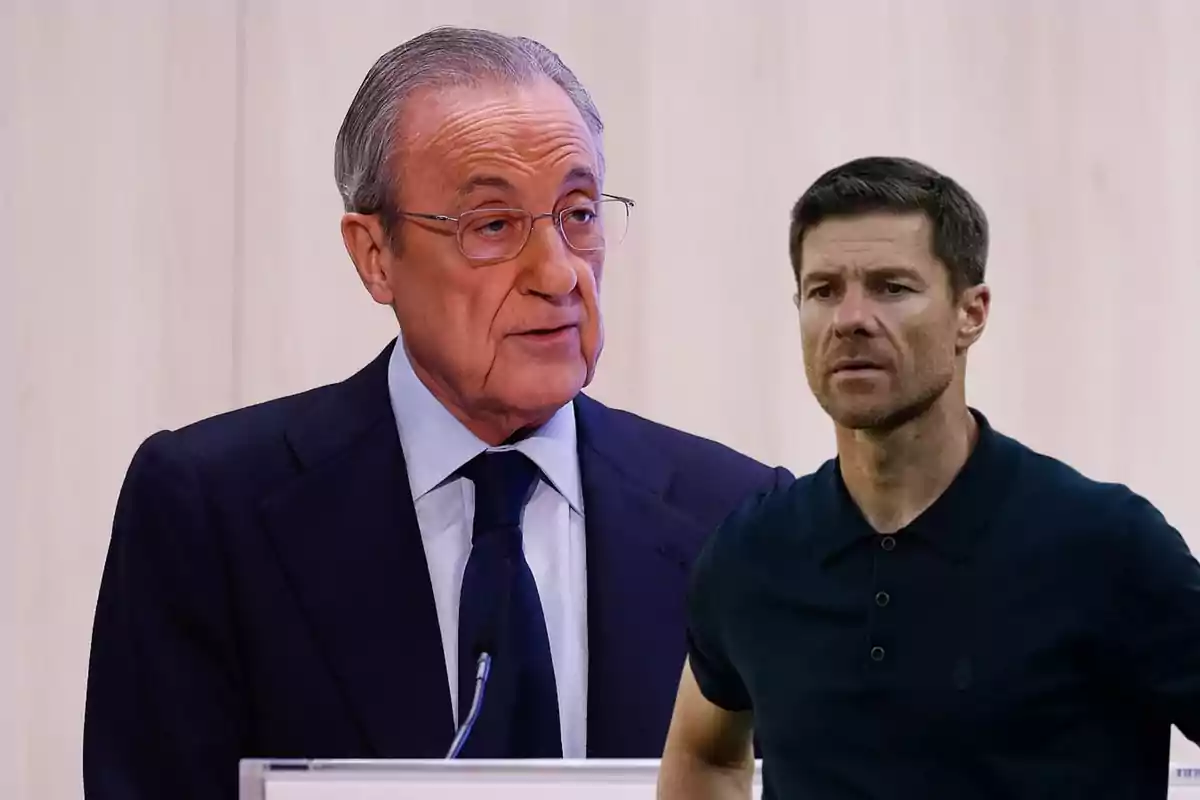 Dos hombres en primer plano, uno de ellos lleva traje y gafas mientras habla frente a un micrófono, el otro viste una camiseta polo oscura y observa hacia adelante.