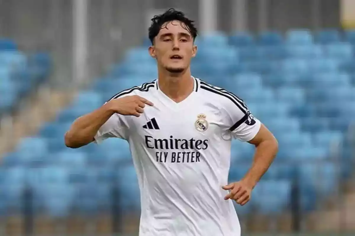 Futbolista con uniforme blanco del Real Madrid celebrando en un estadio con gradas azules de fondo Futbolista con uniforme blanco del Real Madrid celebrando en un estadio con gradas azules de fondo