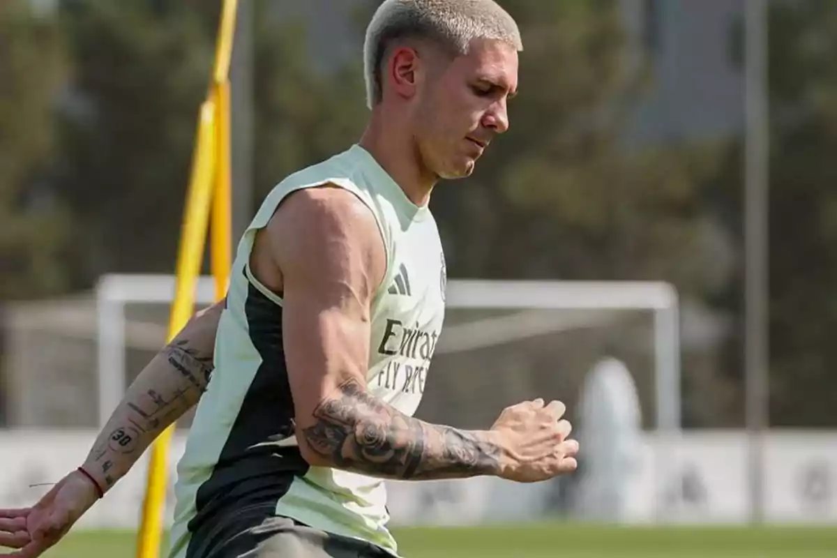 Futbolista entrenando en un campo de fútbol con camiseta sin mangas y varios tatuajes en el brazo Futbolista entrenando en un campo de fútbol con camiseta sin mangas y varios tatuajes en el brazo