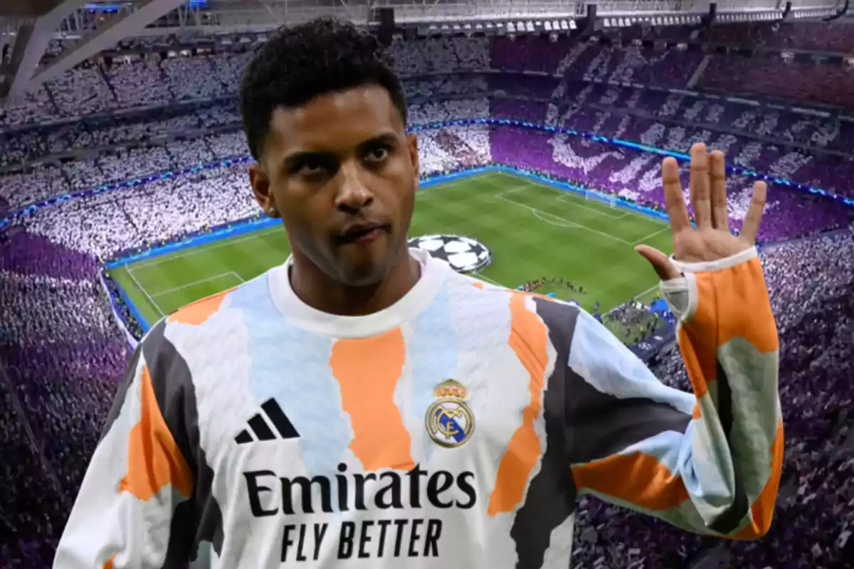 Jugador del Real Madrid con uniforme de entrenamiento levantando la mano en un estadio lleno durante un partido importante de fútbol