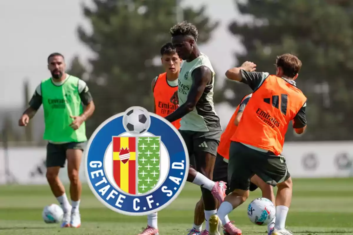 Players training on a soccer field wearing bibs of different colors, with the Getafe C.F. crest in the foreground.