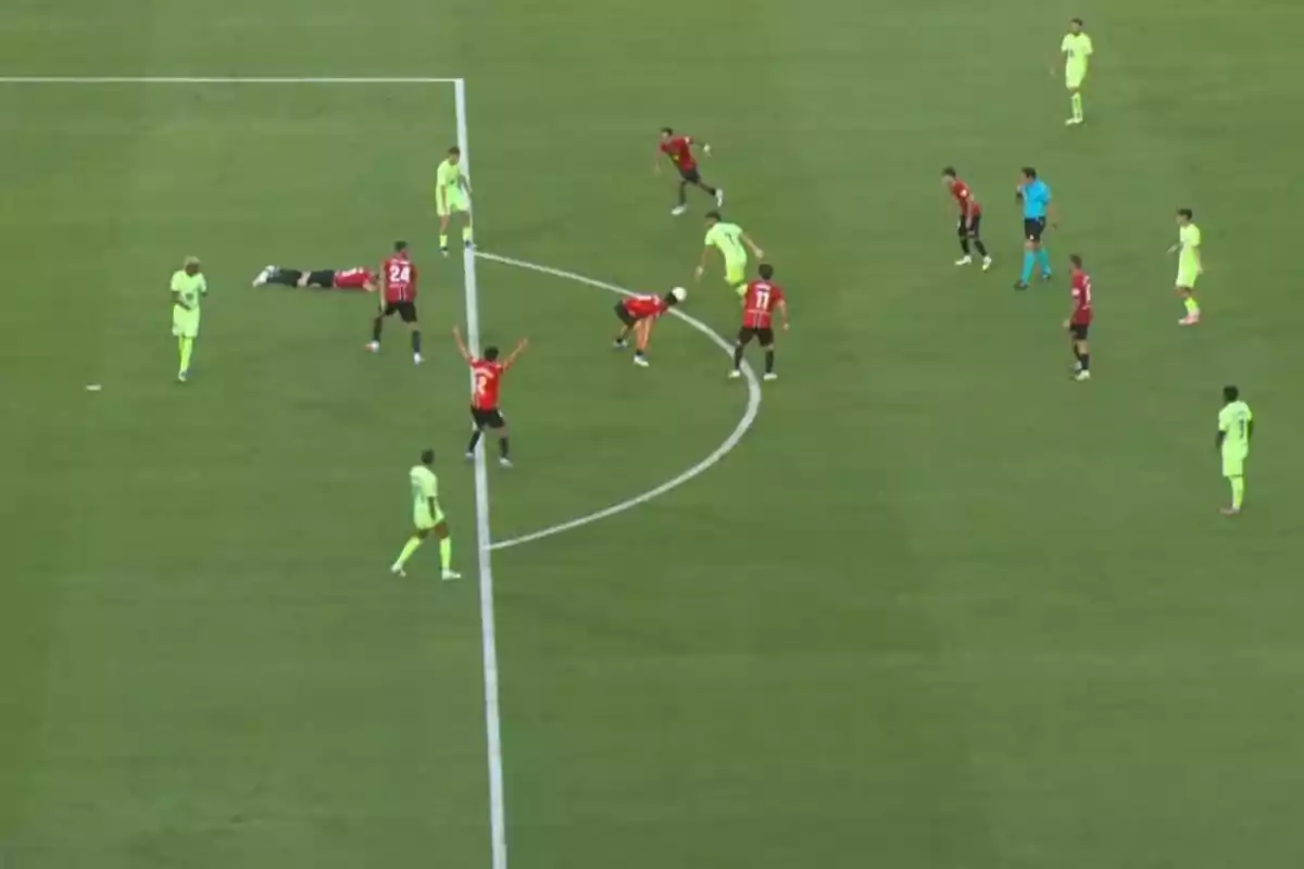 Jugadores de fútbol disputan el balón cerca del área mientras un árbitro observa y un jugador está en el suelo Jugadores de fútbol disputan el balón cerca del área mientras un árbitro observa y un jugador está en el suelo
