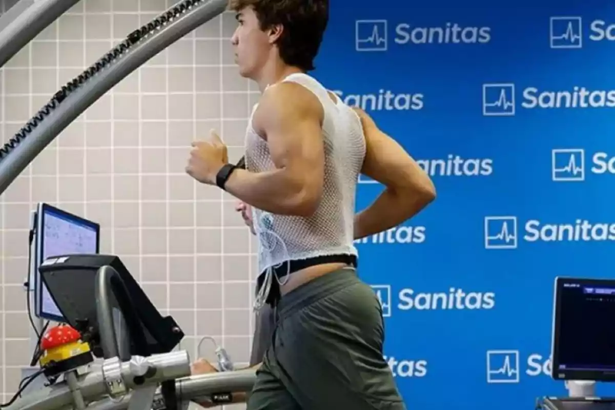 Joven corriendo en una cinta de correr durante una prueba médica con sensores en el torso y pantallas de monitoreo alrededor Joven corriendo en una cinta de correr durante una prueba médica con sensores en el torso y pantallas de monitoreo alrededor