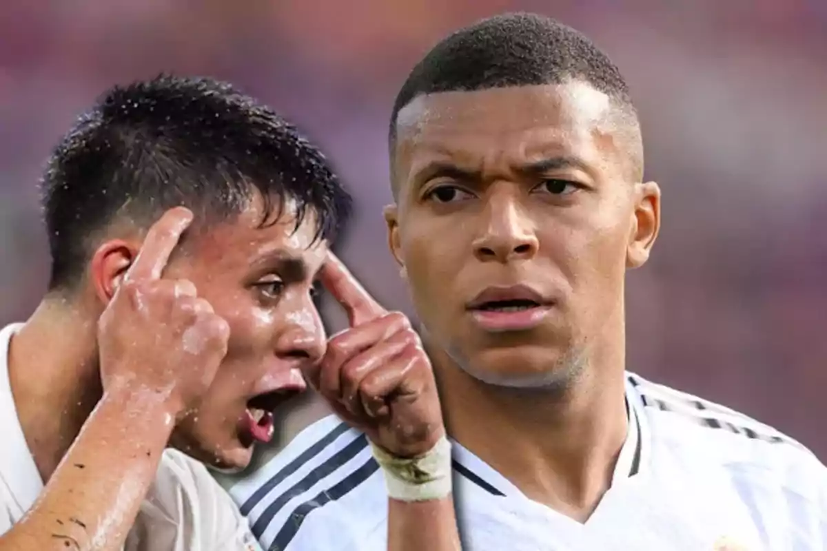 Dos futbolistas con uniforme blanco, uno de ellos señalando su cabeza con ambos dedos y el otro mirando al frente con expresión seria