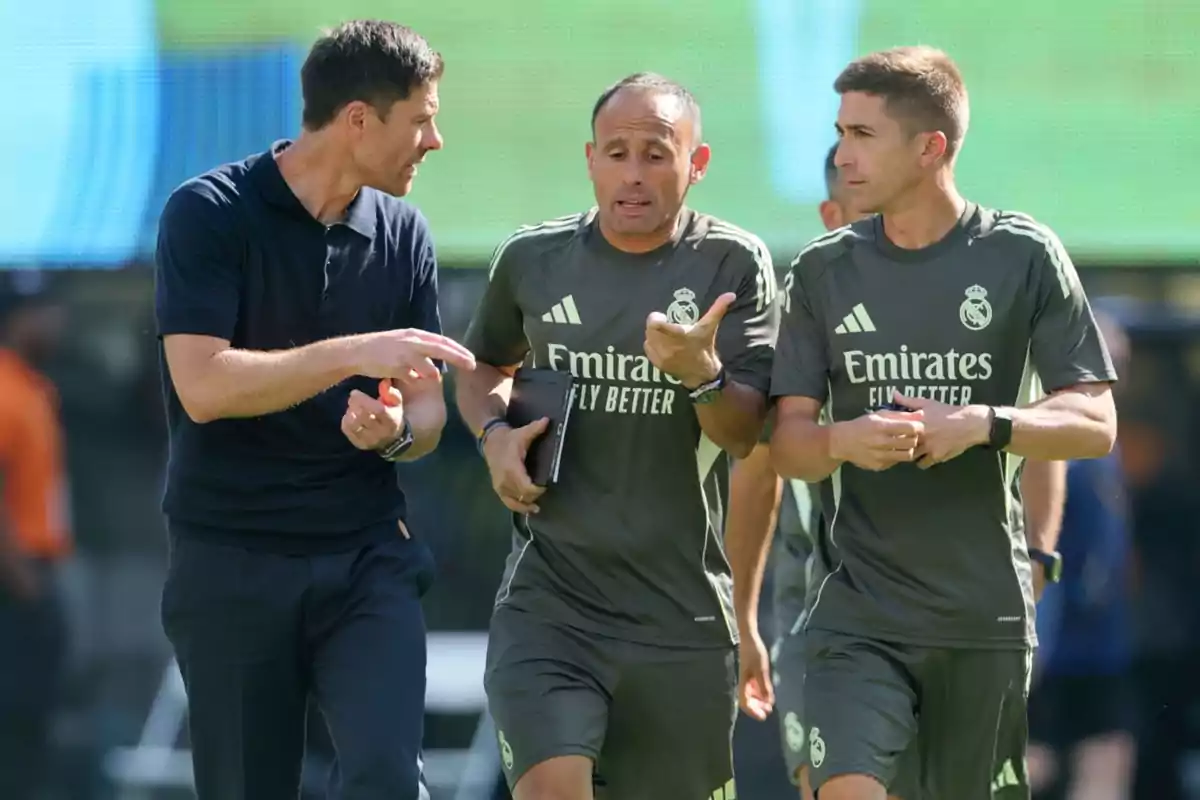Three Real Madrid coaches talk while walking across the training field. Three Real Madrid coaches talk while walking across the training field.