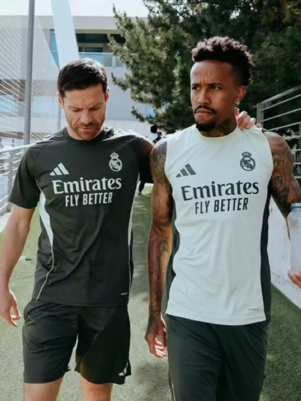 Dos jugadores del Real Madrid caminando juntos en un campo de entrenamiento mientras conversan Dos jugadores del Real Madrid caminando juntos en un campo de entrenamiento mientras conversan