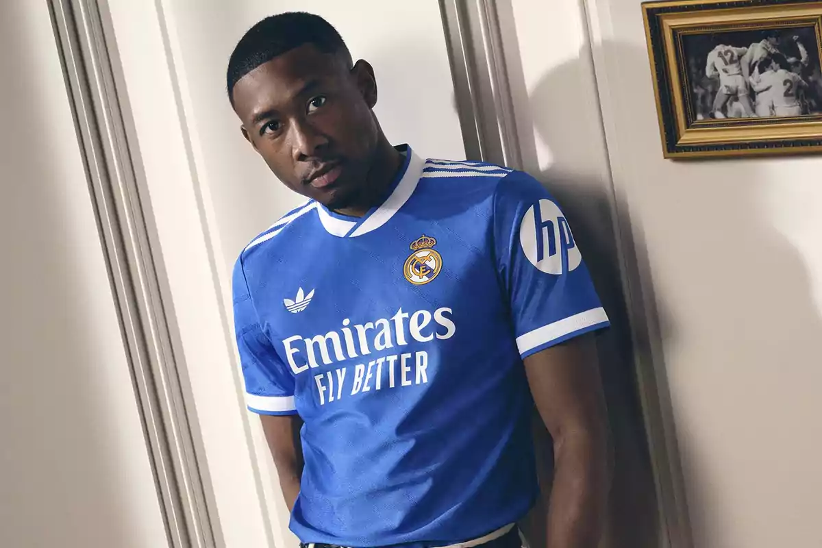 Soccer player wearing a blue Real Madrid jersey posing next to a white wall and a painting in the background Soccer player wearing a blue Real Madrid jersey posing next to a white wall and a painting in the background