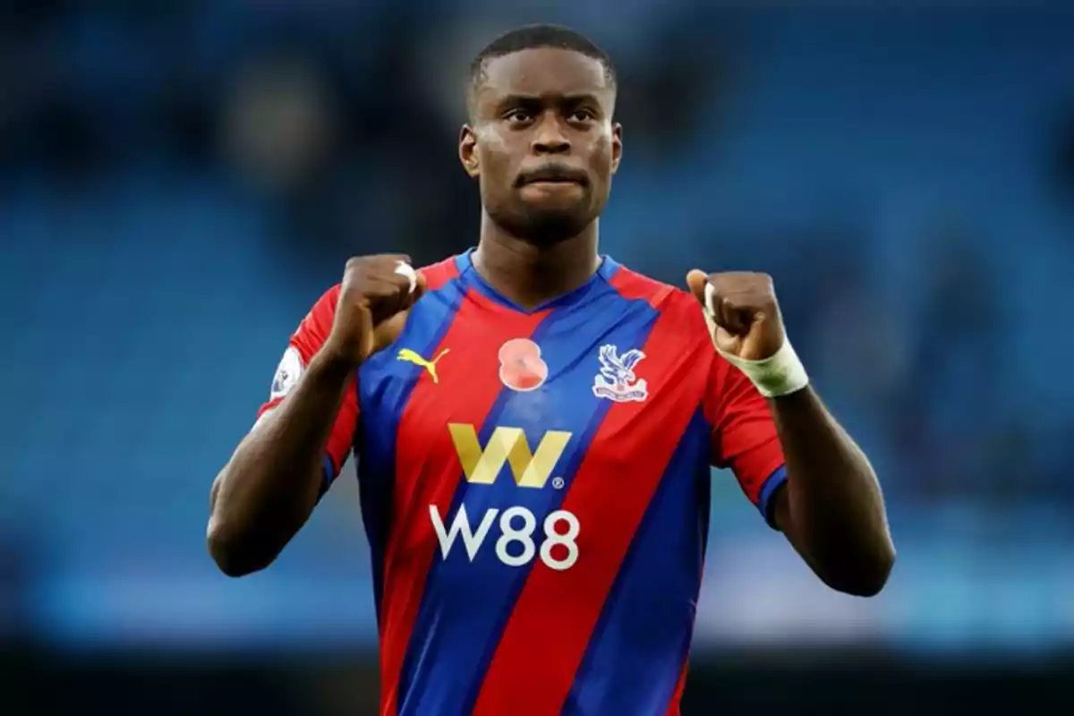 Soccer player in a Crystal Palace uniform celebrating with fists raised in a stadium Soccer player in a Crystal Palace uniform celebrating with fists raised in a stadium