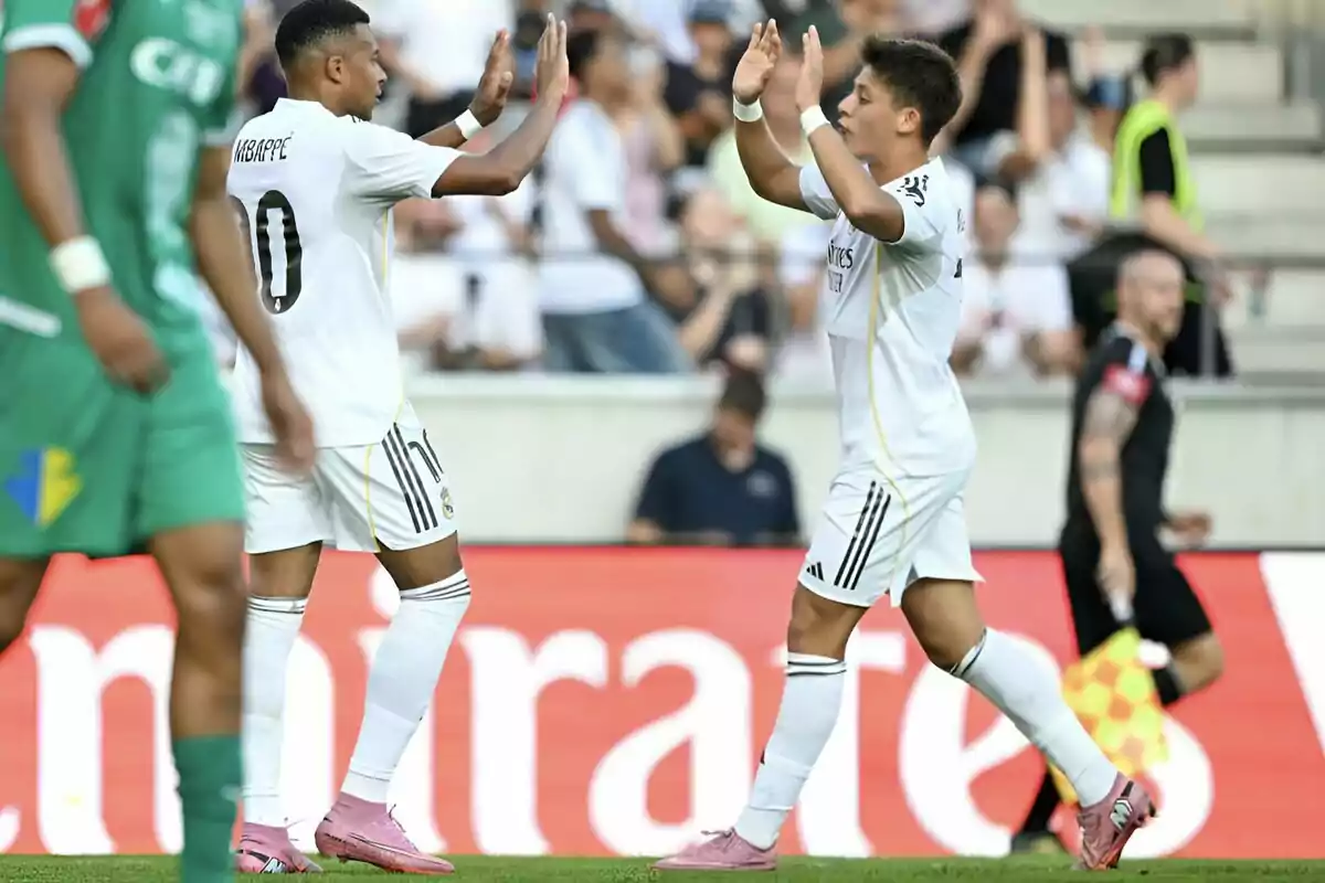 Two players in white uniforms celebrate with a high five on the field during a match. Two players in white uniforms celebrate with a high five on the field during a match.