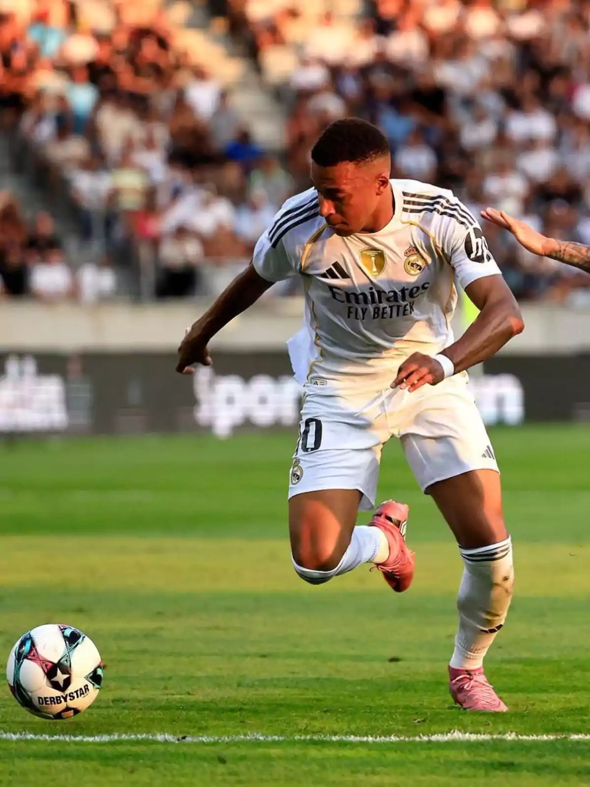 Real Madrid player running after the ball during a match in a stadium full of spectators Real Madrid player running after the ball during a match in a stadium full of spectators
