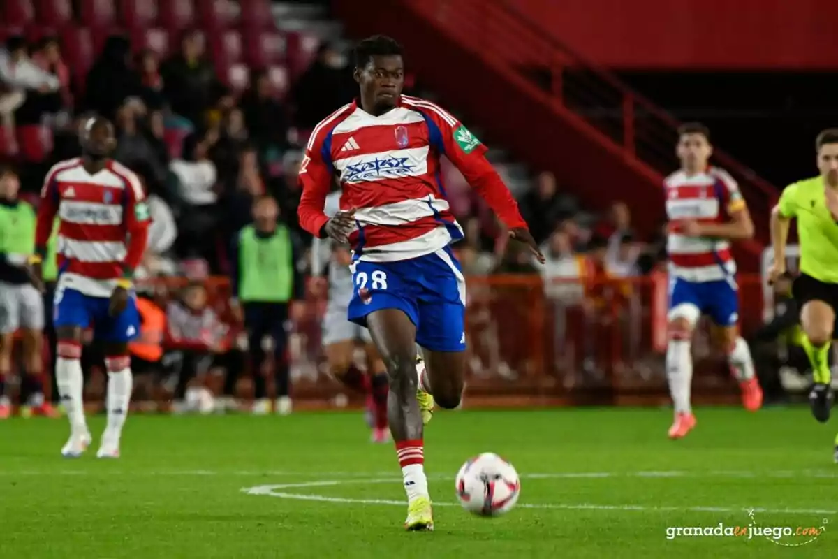 Granada CF player running with the ball during a match in a stadium full of spectators Granada CF player running with the ball during a match in a stadium full of spectators