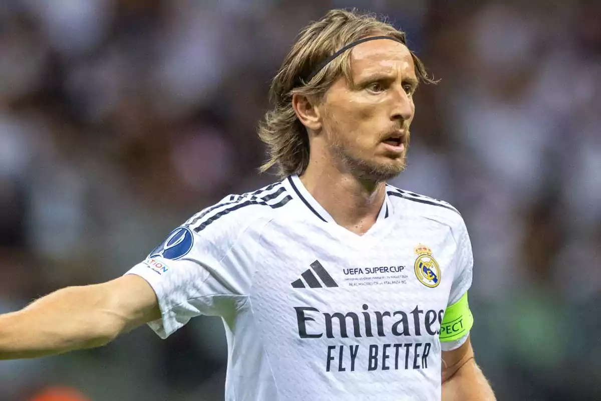 Futbolista con uniforme blanco del Real Madrid durante un partido llevando el gafete de capitán y una banda en la cabeza