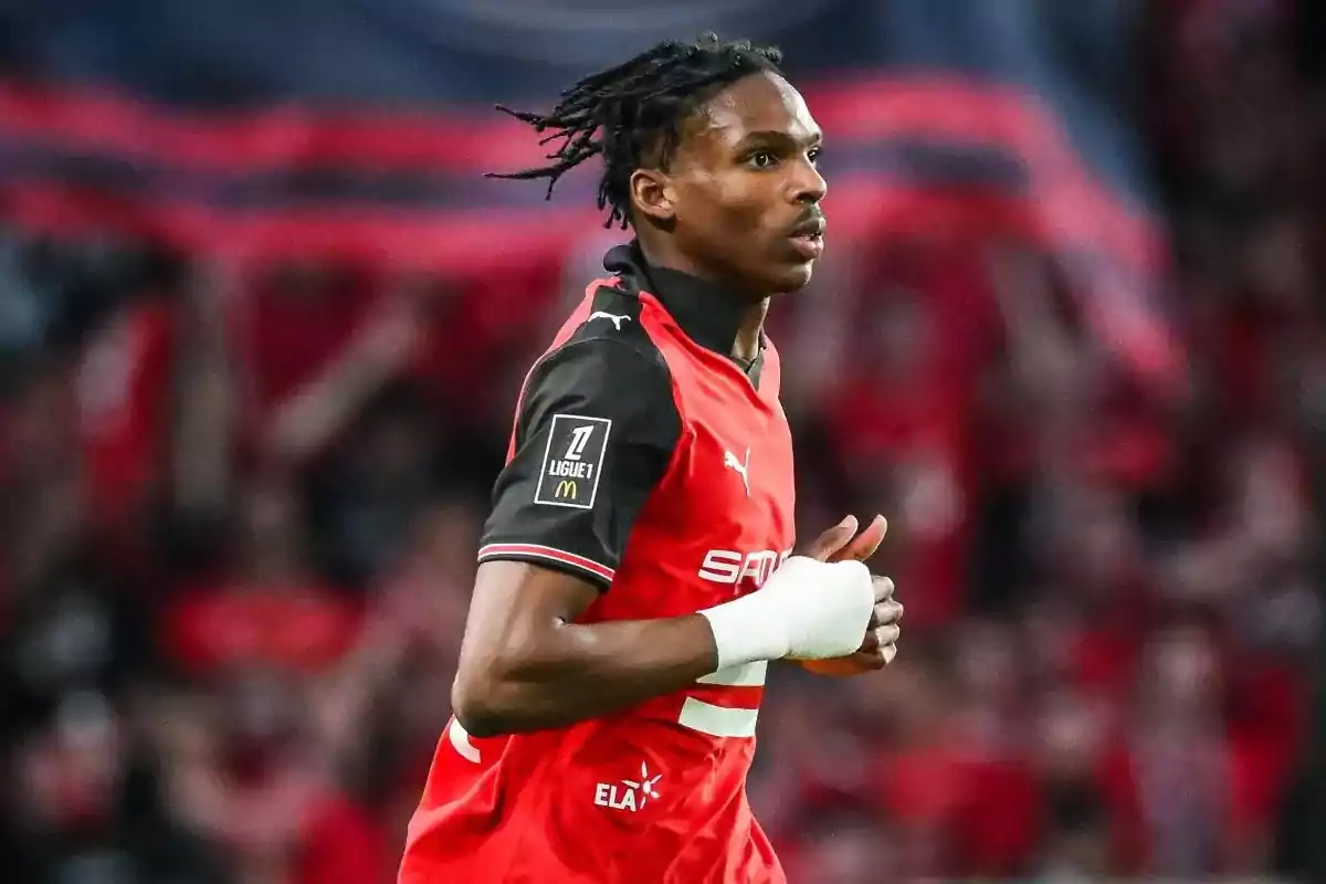 Futbolista con uniforme rojo y negro corriendo en un estadio con público de fondo Futbolista con uniforme rojo y negro corriendo en un estadio con público de fondo