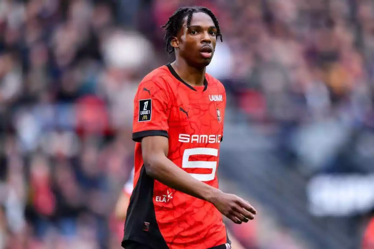 Soccer player wearing the red and black uniform of Stade Rennais in a match Soccer player wearing the red and black uniform of Stade Rennais in a match