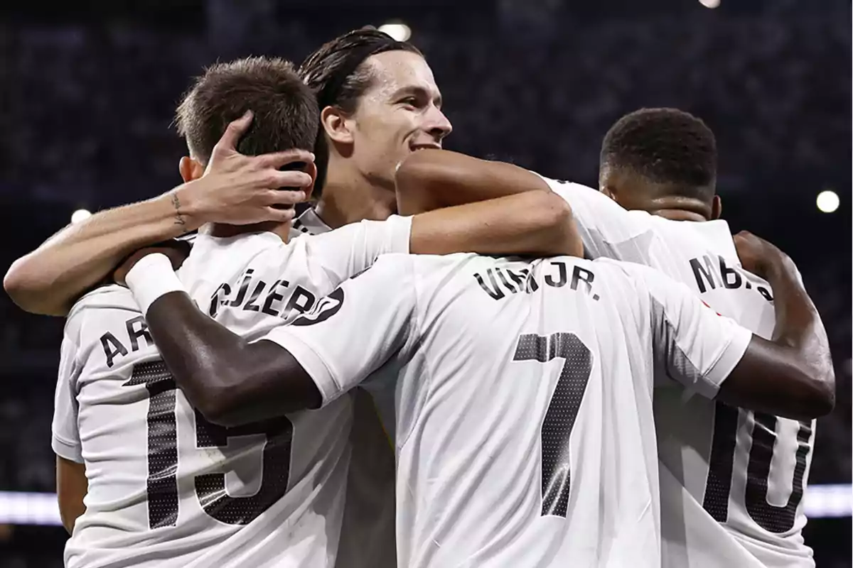 Soccer players celebrate hugging after scoring a goal during a match.