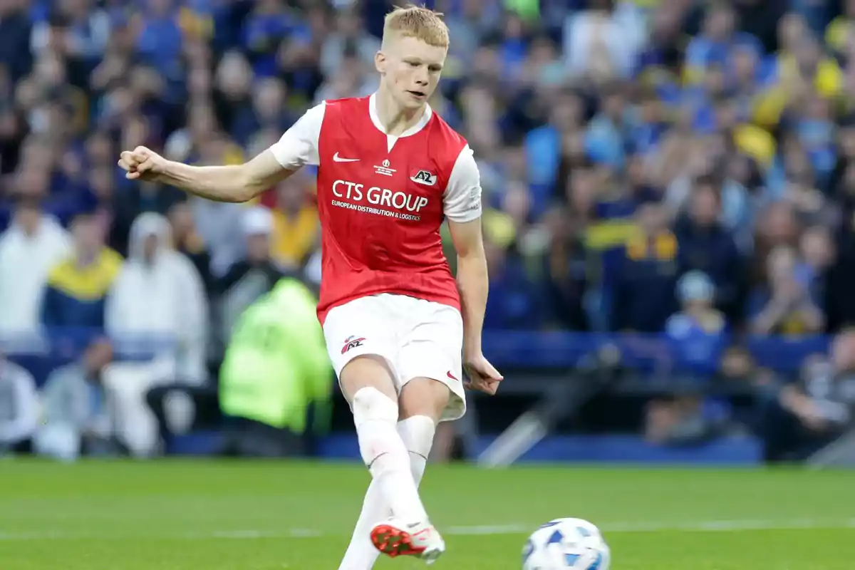 AZ Alkmaar player in a red and white uniform kicking a ball in a stadium full of spectators AZ Alkmaar player in a red and white uniform kicking a ball in a stadium full of spectators
