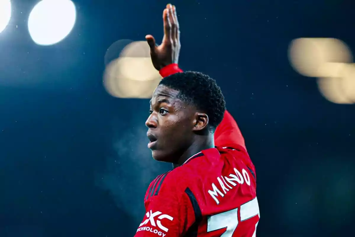 Soccer player in a red uniform raising his hand during a night game Soccer player in a red uniform raising his hand during a night game