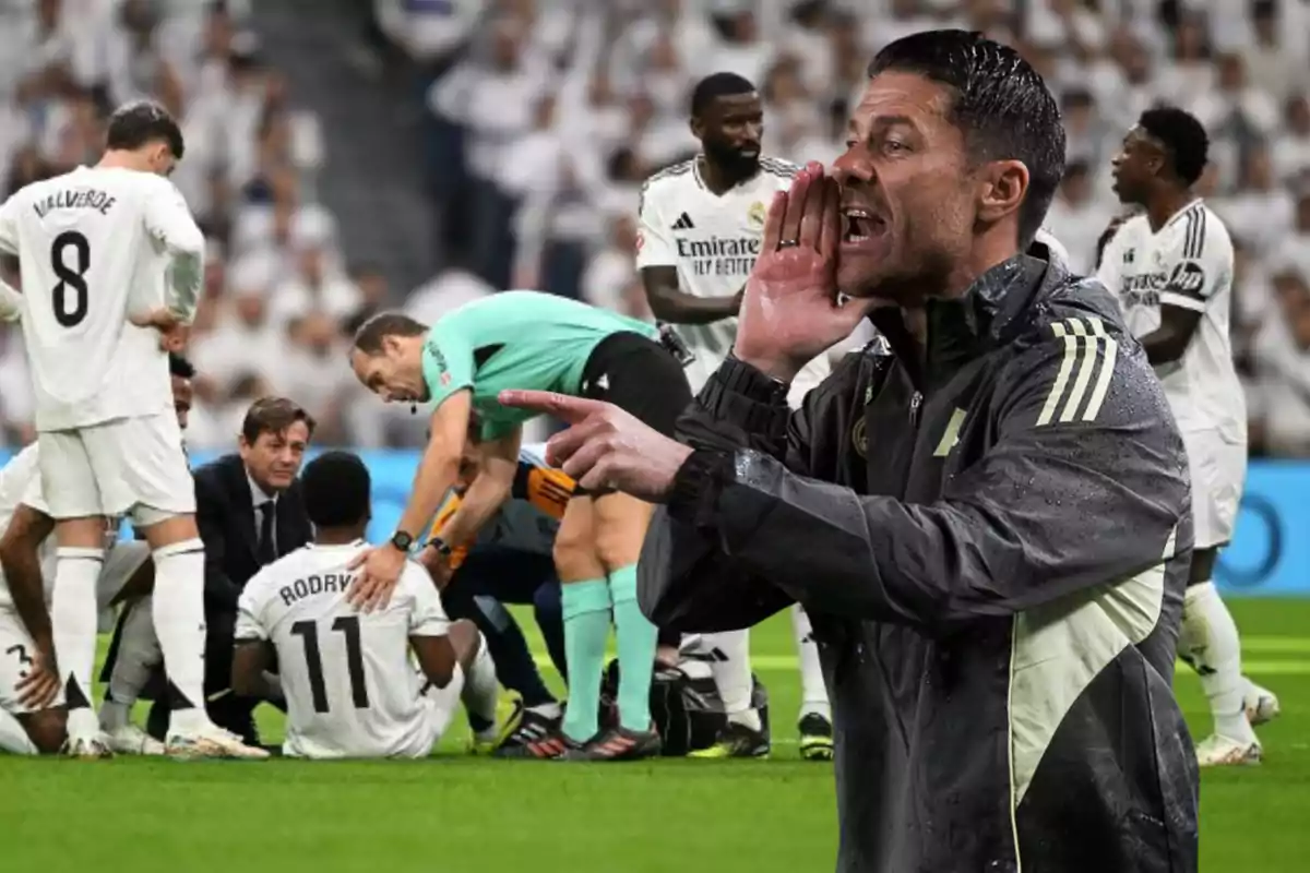 Un entrenador da indicaciones en primer plano mientras al fondo un grupo de jugadores y un árbitro atienden a un futbolista lesionado en el campo
