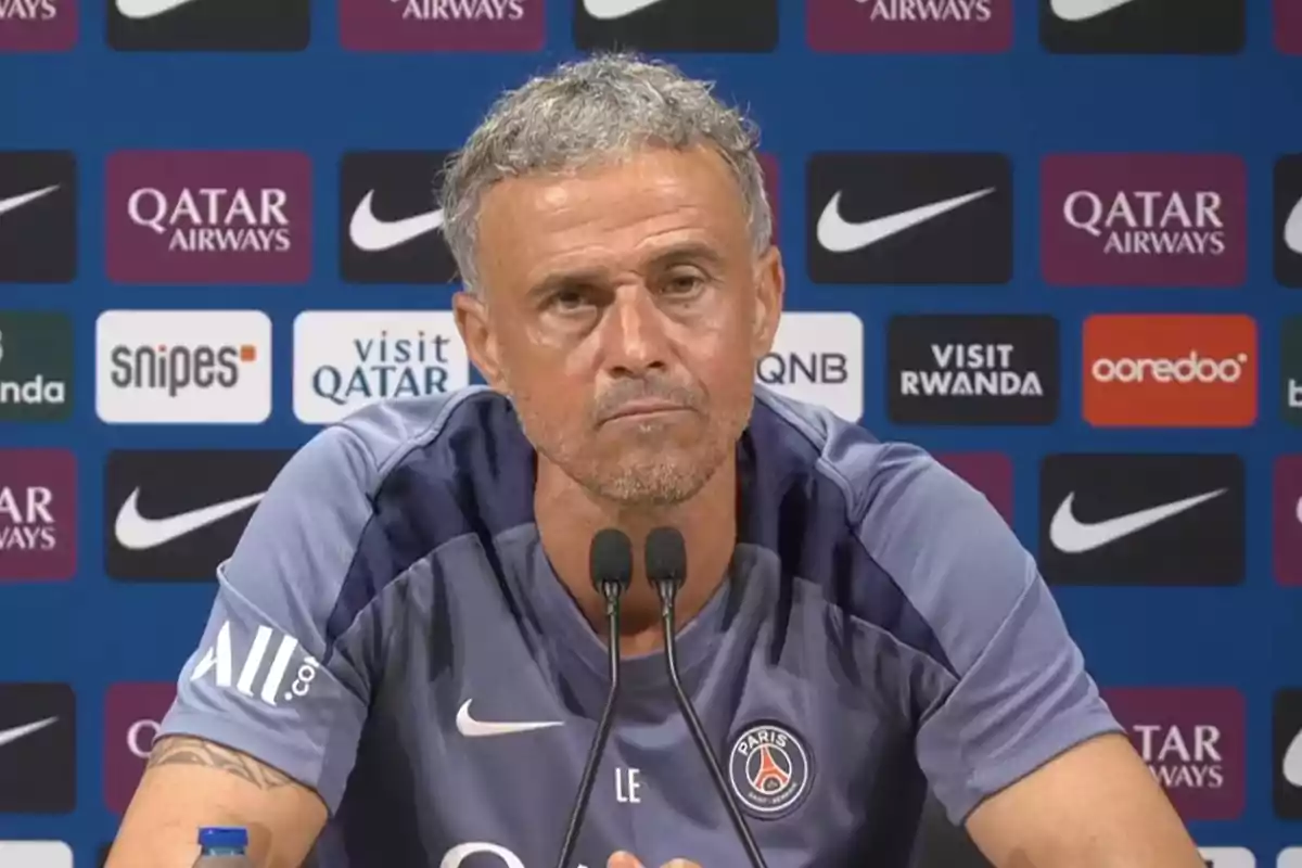 Hombre con camiseta del PSG hablando en una rueda de prensa con fondo de patrocinadores deportivos