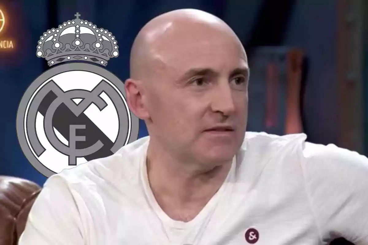 Bald man in a white t-jersey sitting in front of a background featuring the Real Madrid crest