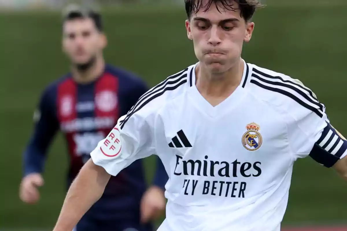 Jugador del Real Madrid con el uniforme blanco en acción durante un partido de fútbol con un rival desenfocado al fondo Jugador del Real Madrid con el uniforme blanco en acción durante un partido de fútbol con un rival desenfocado al fondo