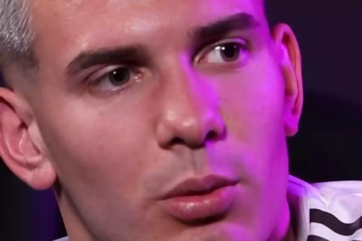 Primer plano de un hombre con expresión seria iluminado con luz morada Primer plano de un hombre con expresión seria iluminado con luz morada