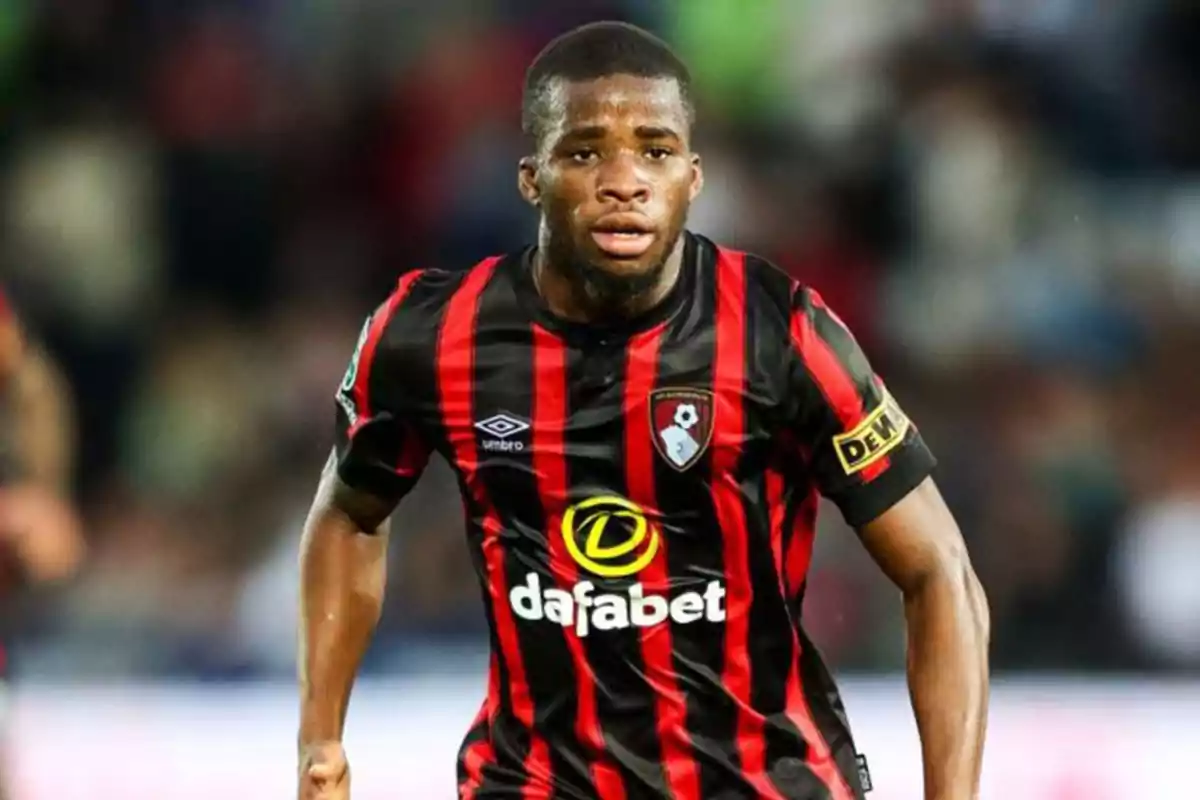 Futbolista con uniforme negro y rojo del Bournemouth corriendo en el campo durante un partido Futbolista con uniforme negro y rojo del Bournemouth corriendo en el campo durante un partido